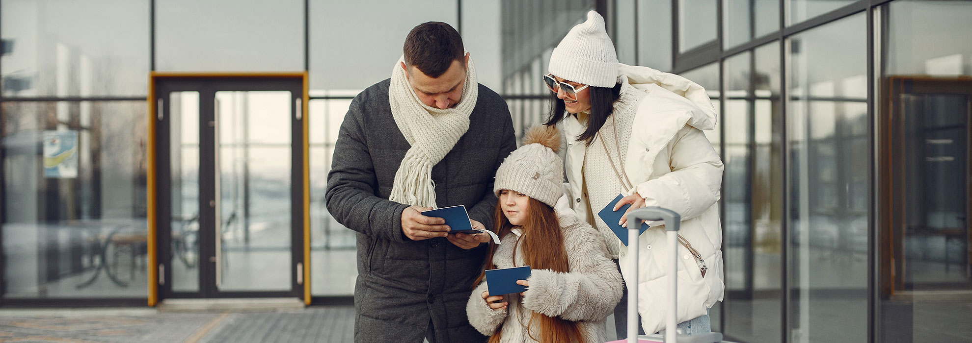 family-standing-outdoors-with-luggage-and-checking-ASDER25